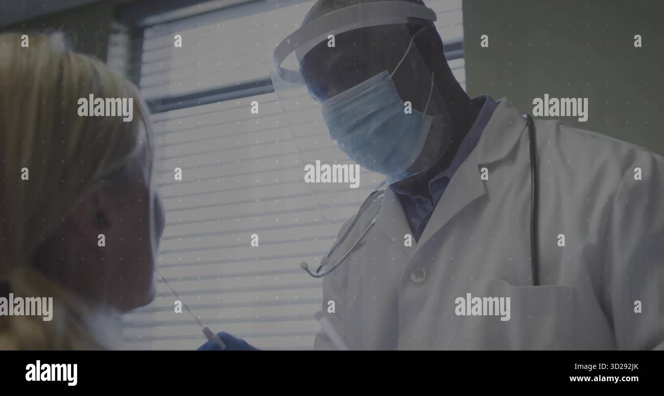 Medico che indossa camice da laboratorio e guanti per raccogliere il tampone dal paziente nella sala esame, con visiera protettiva Foto Stock