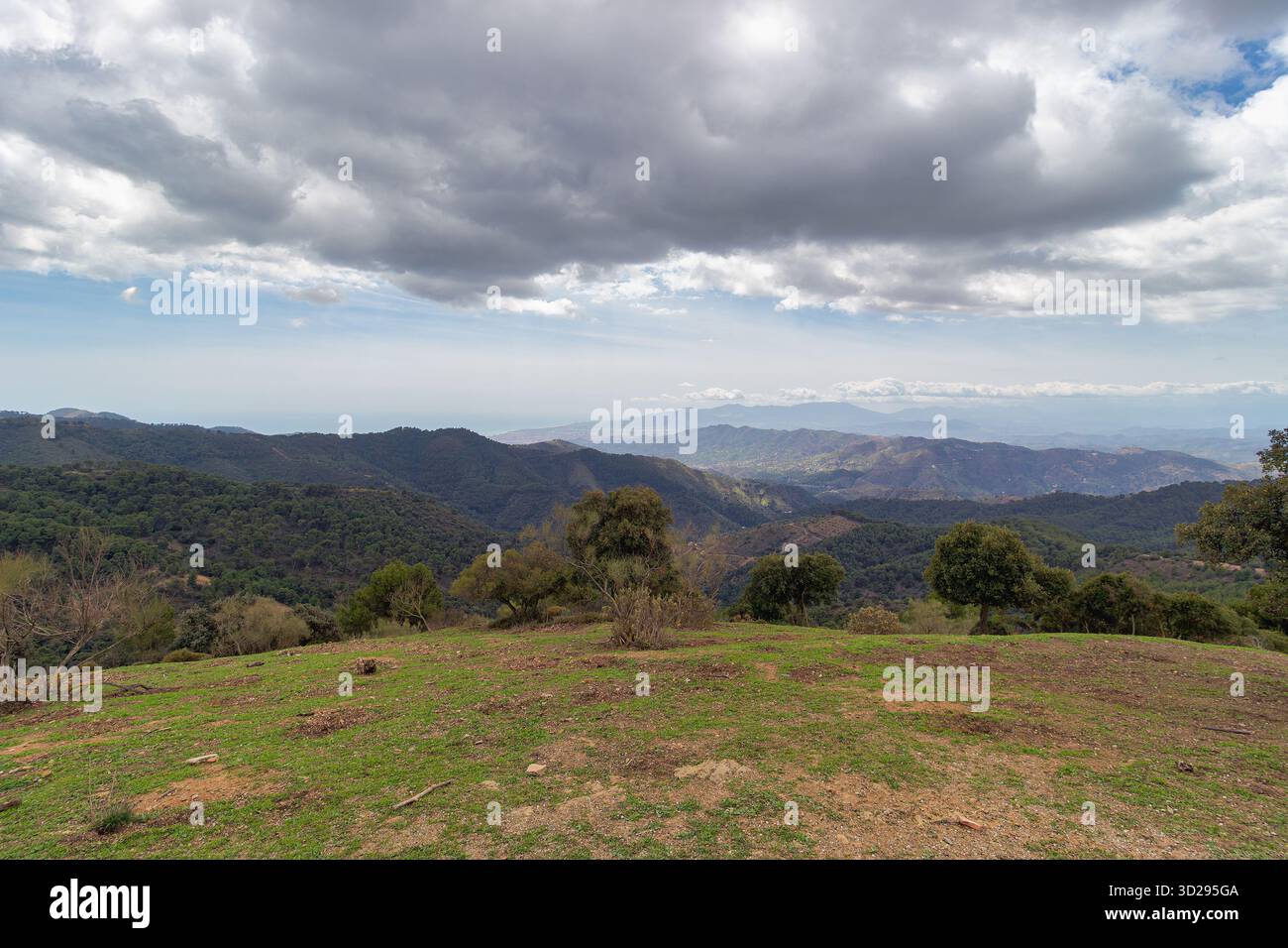 Ampia vista panoramica del paesaggio montuoso del Parco naturale Montes de Málaga, con il Mar Mediterraneo visibile all'orizzonte e nuvoloso sk Foto Stock