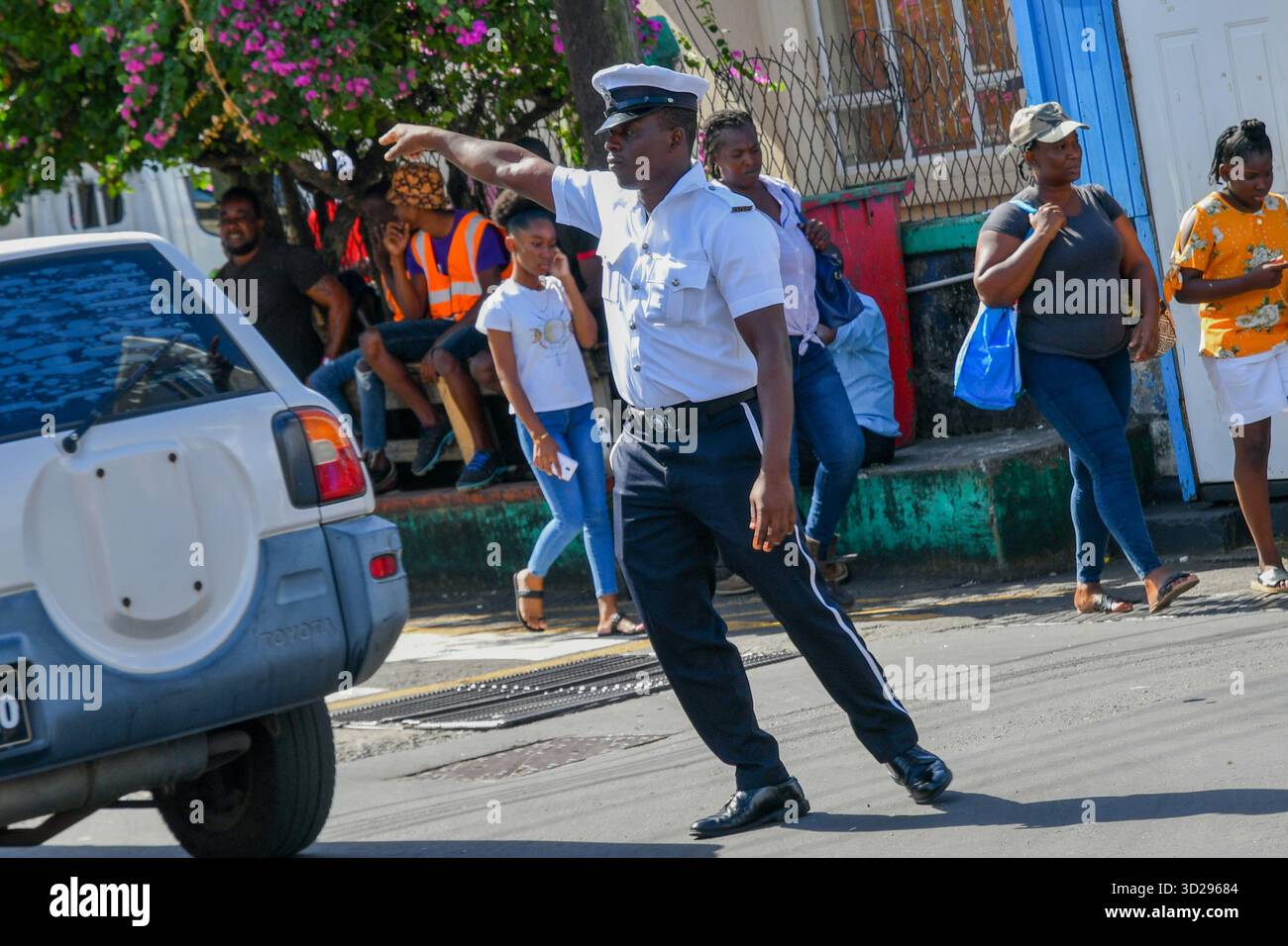 L'agente di polizia animato del Royal Saint Vincent e della forza di polizia di Grenadine dirige il traffico su Kingstown Street mentre gli acquirenti camminano nelle vicinanze Foto Stock