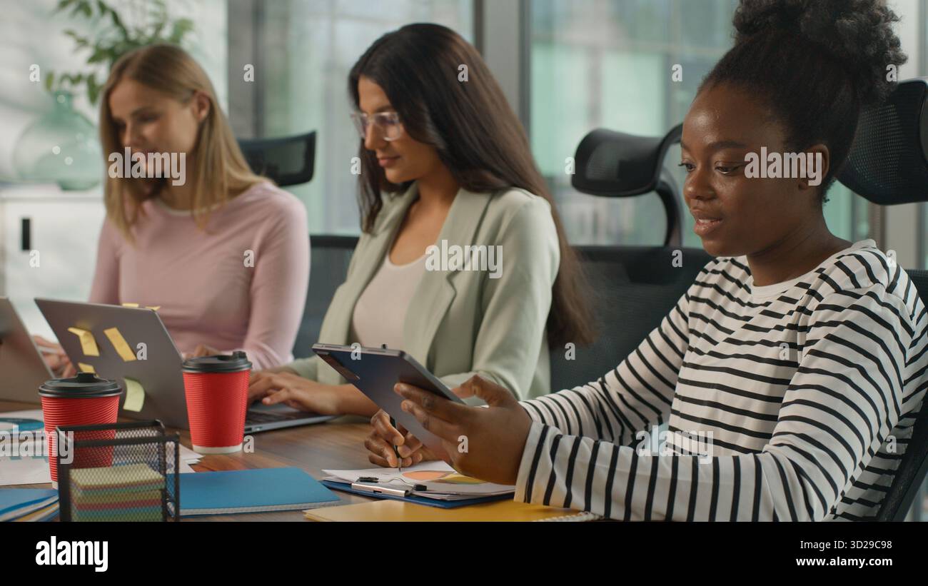 Tre donne d'affari informali multirazziali che lavorano in ufficio donne d'affari informali che lavorano con computer portatili collaborazioni di collaborazione Foto Stock