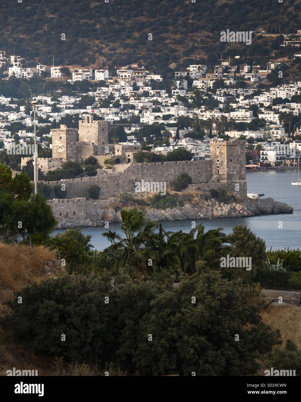 Vista di un castello medievale che si erge maestosamente sullo sfondo del mare e di un villaggio collinare, con le sue mura di pietra intrise di storia, Bodrum, Mu Foto Stock