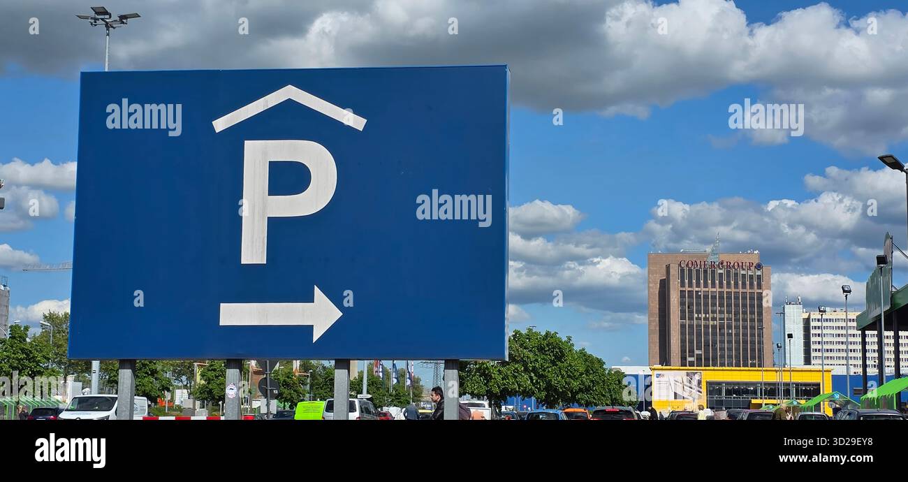 Berlino, Germania - 5 maggio 2025: L'insegna del parcheggio presenta una freccia direzionale contro un cielo blu vibrante con nuvole. - Immagine stock catturata con smartphone