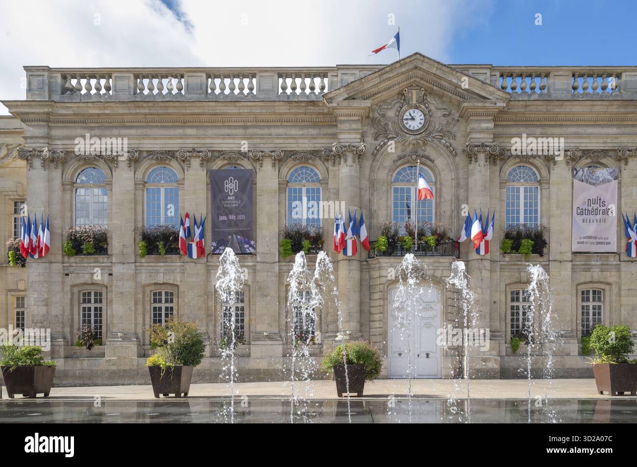 La facciata classicista del municipio di Beauvais (Hotel de Ville) domina Place Jeanne Hachette. Le fontane del pavimento possono essere viste in azione in primo piano Foto Stock