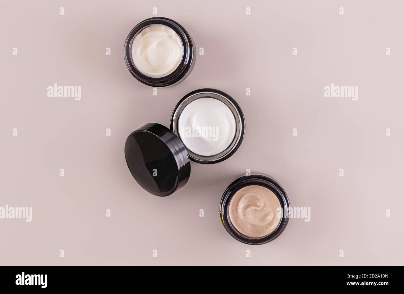 Un set di vasetti di vetro con crema cosmetica di diversi colori per la cura della pelle del viso e del corpo. Design. imballaggio. Presentazione del prodotto. Vista dall'alto. mockup Foto Stock