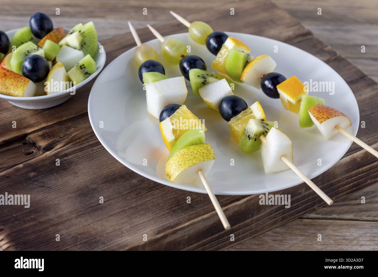 Canape vegetariana di frutta agli spiedini con uva, kiwi e mango su sfondo di legno. snack per il catering Foto Stock