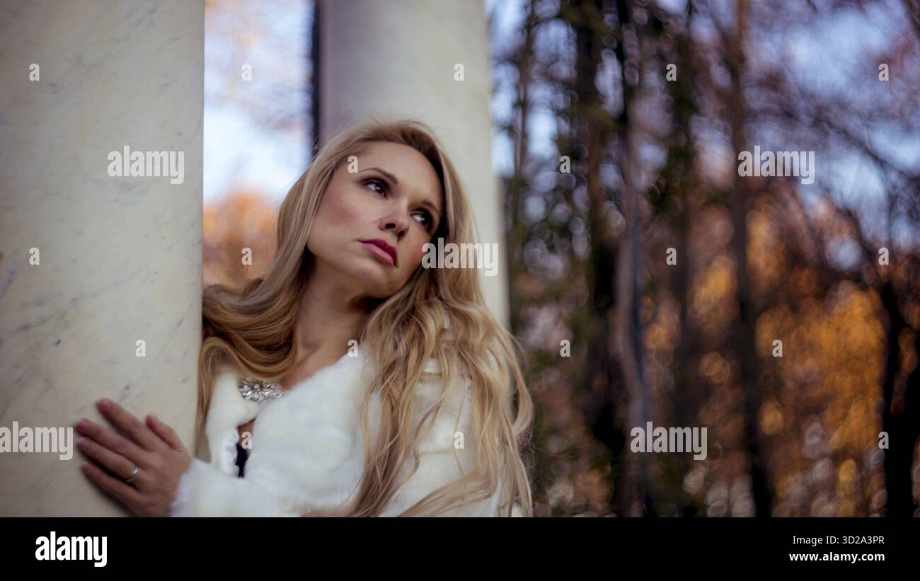 Pelliccia, scena dell'autunno e dell'inverno, bella donna bionda con gesti di malinconia vestita con cappotto grigio Foto Stock