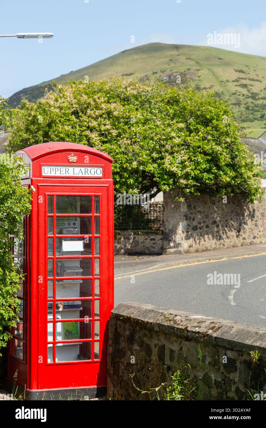 Una cabina telefonica britannica rossa con il nome del villaggio, Upper largo, su di essa e largo Law Hill sullo sfondo. Foto Stock