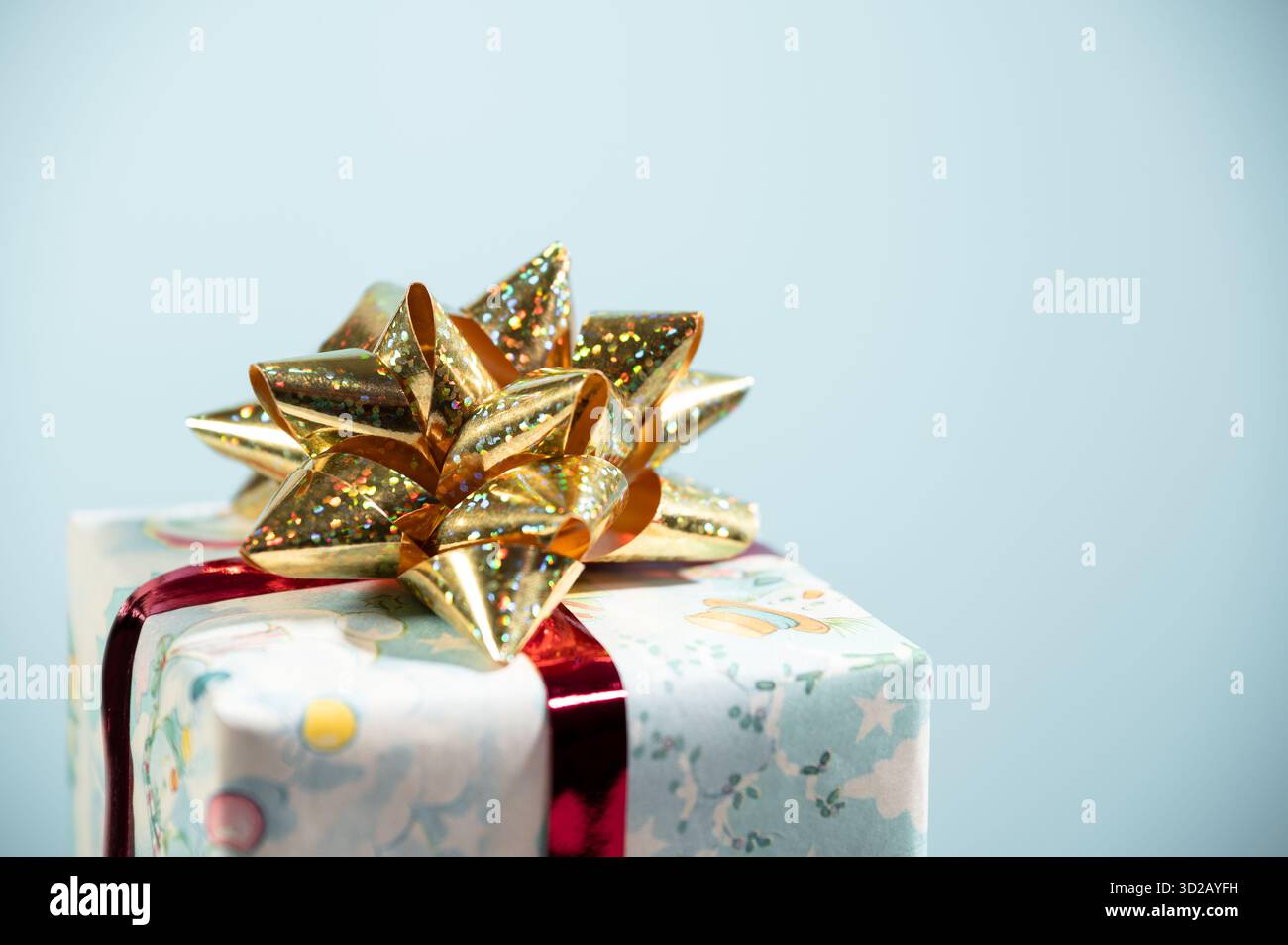 Regalo di Natale con decorazioni e fiocco dorato su sfondo blu. Foto Stock