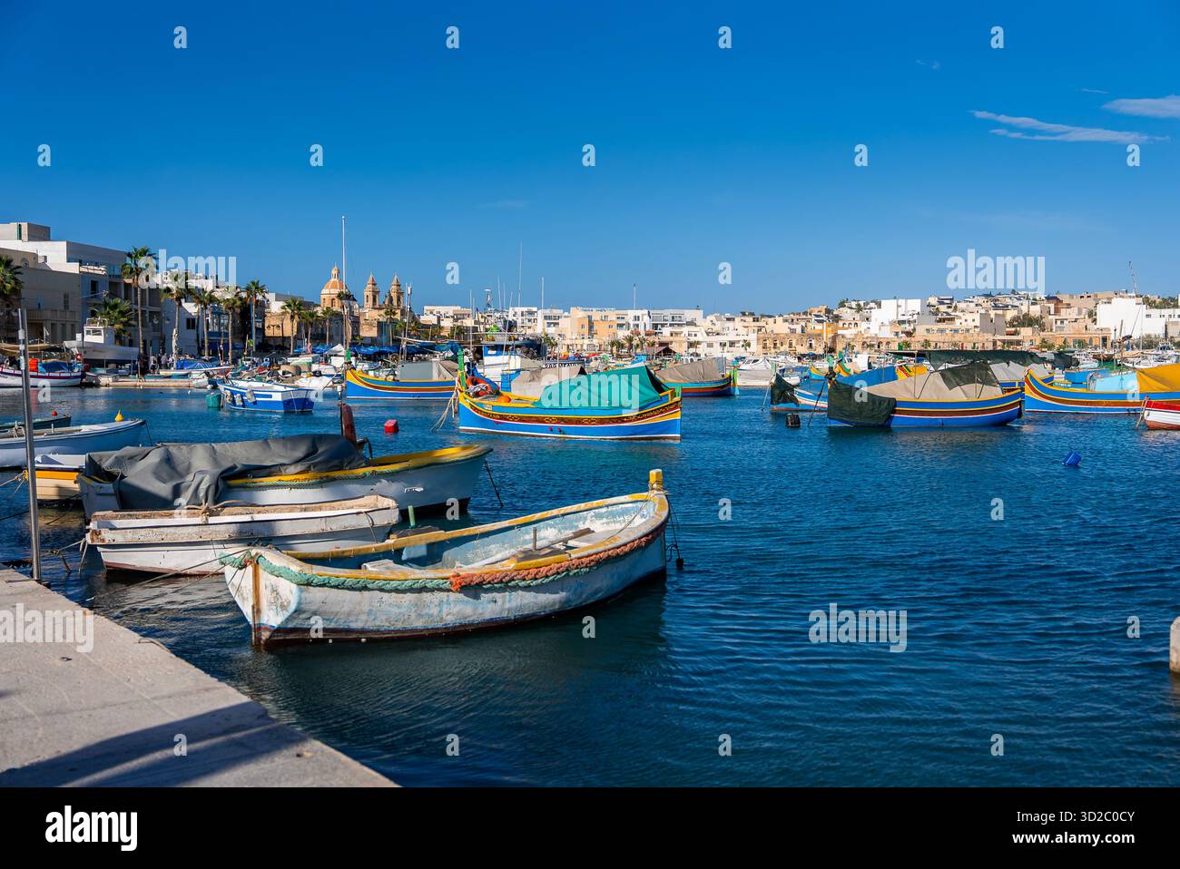 Barche Luzzu nel porto di Marsaxlokk con la Chiesa di nostra Signora di Pompei Foto Stock