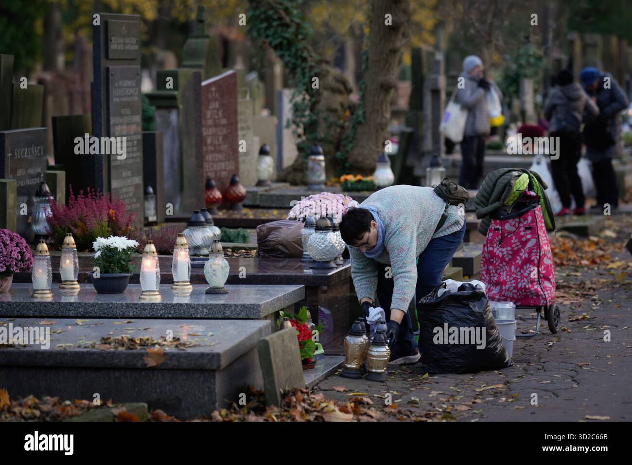 Varsavia, Polonia. 31 ottobre 2025. Una donna colloca candele su una tomba nel cimitero di Powazki a Varsavia, in Polonia, il 31 ottobre 2025. (Foto di Jaap Arriens/Sipa USA) credito: SIPA USA/Alamy Live News Foto Stock