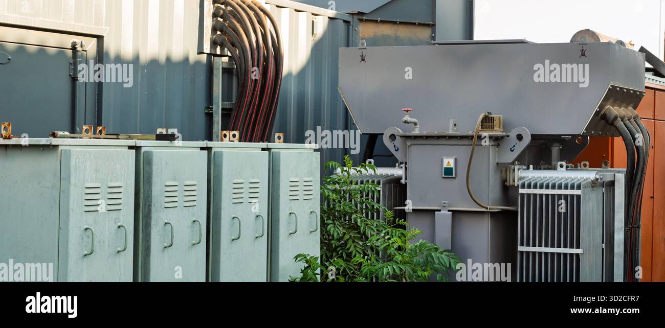 Trasformatore elettrico e armadietti del gruppo di comando. Sia i trasformatori che il gruppo di comando sono componenti essenziali di un sistema di alimentazione elettrica Foto Stock