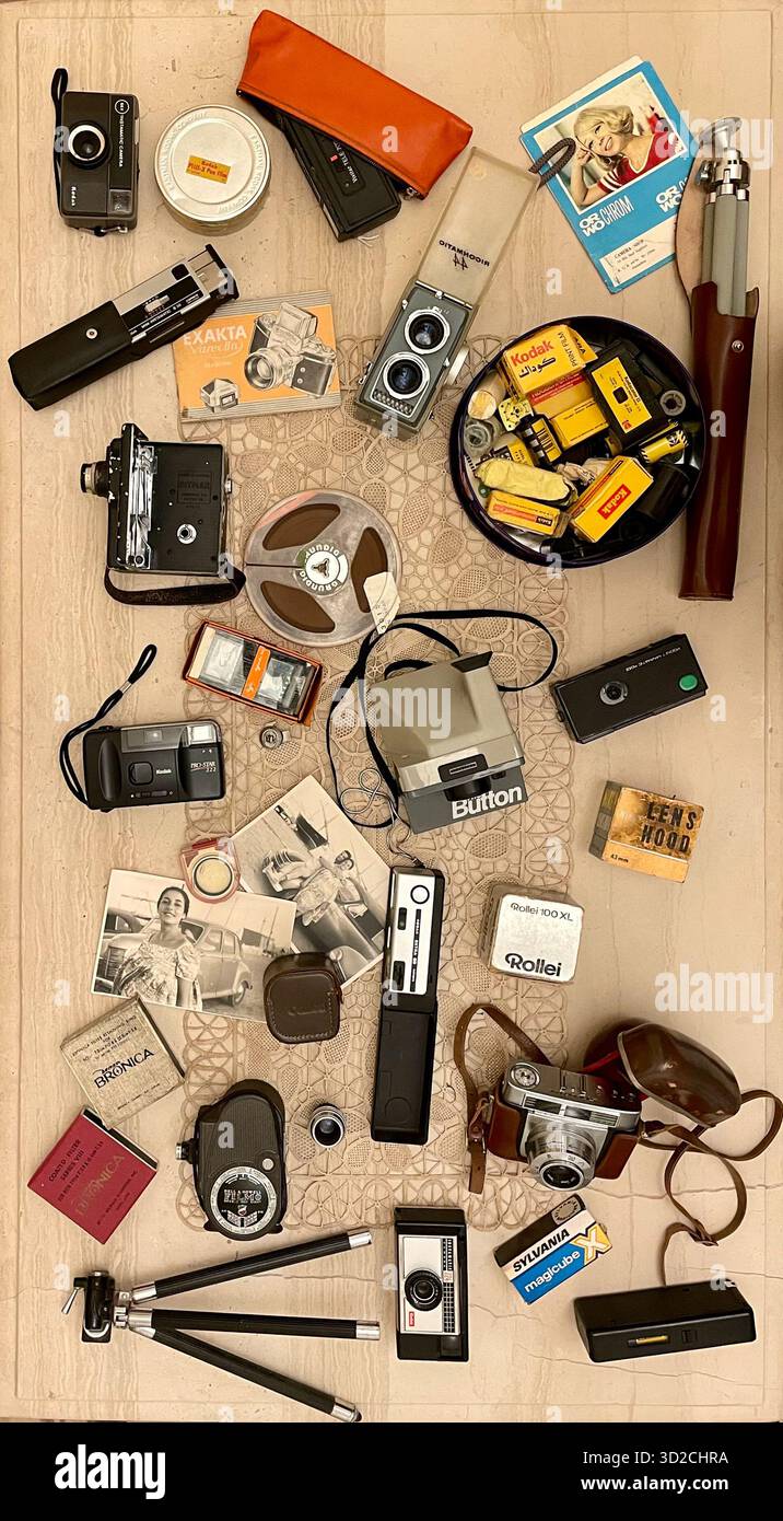 Collezione storica di antiche fotocamere analogiche d'epoca disposte sul tavolo insieme a un vecchio catalogo di cavalletti fotografici Foto Stock