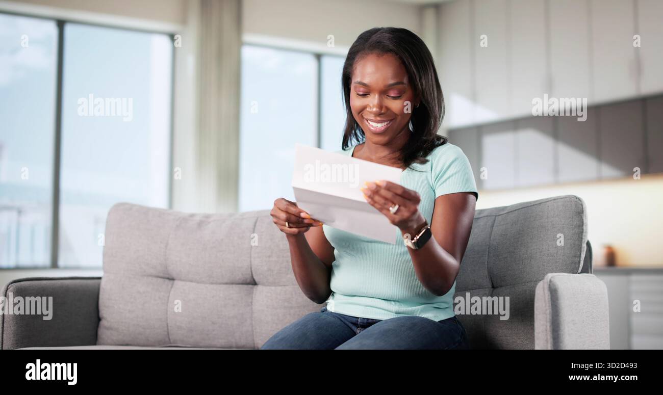 Una donna eccitata legge una lettera positiva, sorridendo gioiosamente a Good News. Foto Stock