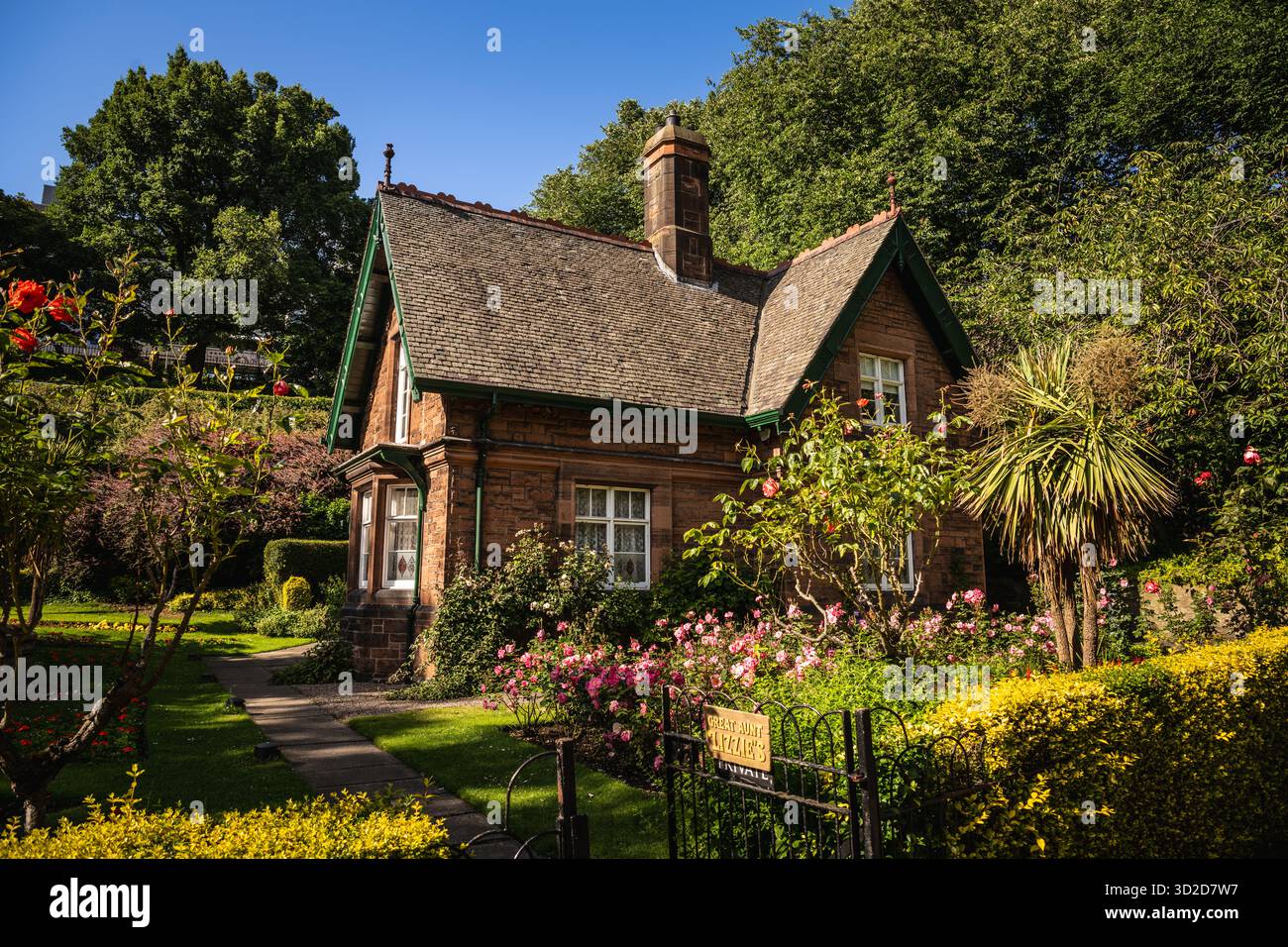 Storico cottage del giardiniere circondato da fiori nei giardini di Princes Street - Edimburgo, Scozia Foto Stock