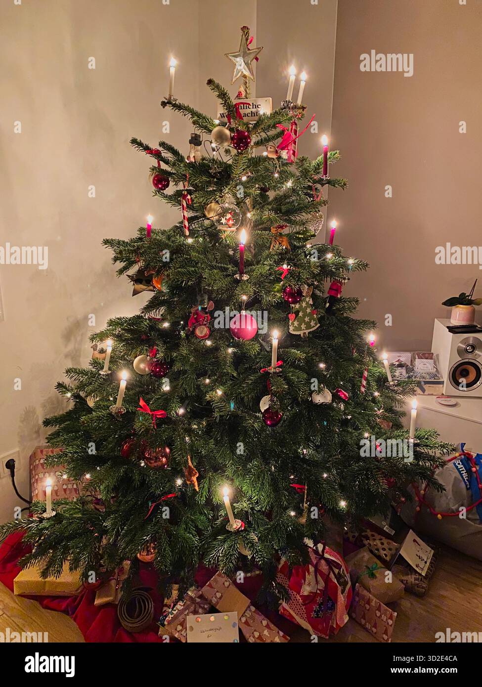 Albero di Natale con candele accese, palle di natale e molti regali avvolti durante le festività natalizie, decorazione moderna, foto di scorta Foto Stock
