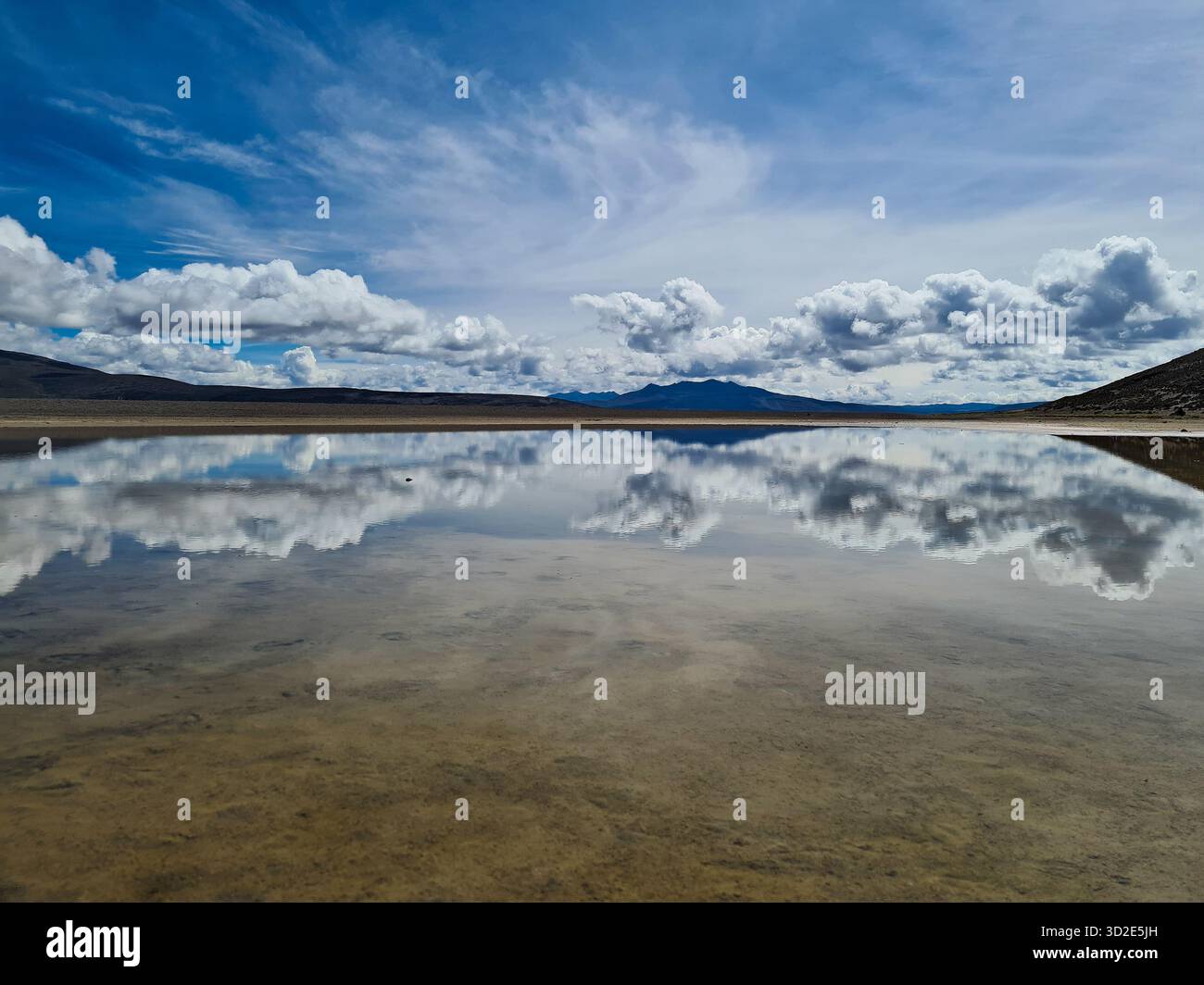 Perfetto riflesso specchio del cielo e delle nuvole in una laguna ad alta quota, in Perù. - Immagine stock catturata con smartphone
