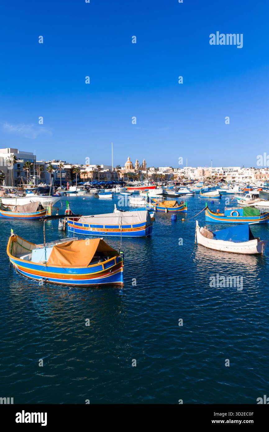 Porto di Marsaxlokk con barche luzzu e torri della Chiesa Parrocchiale Foto Stock