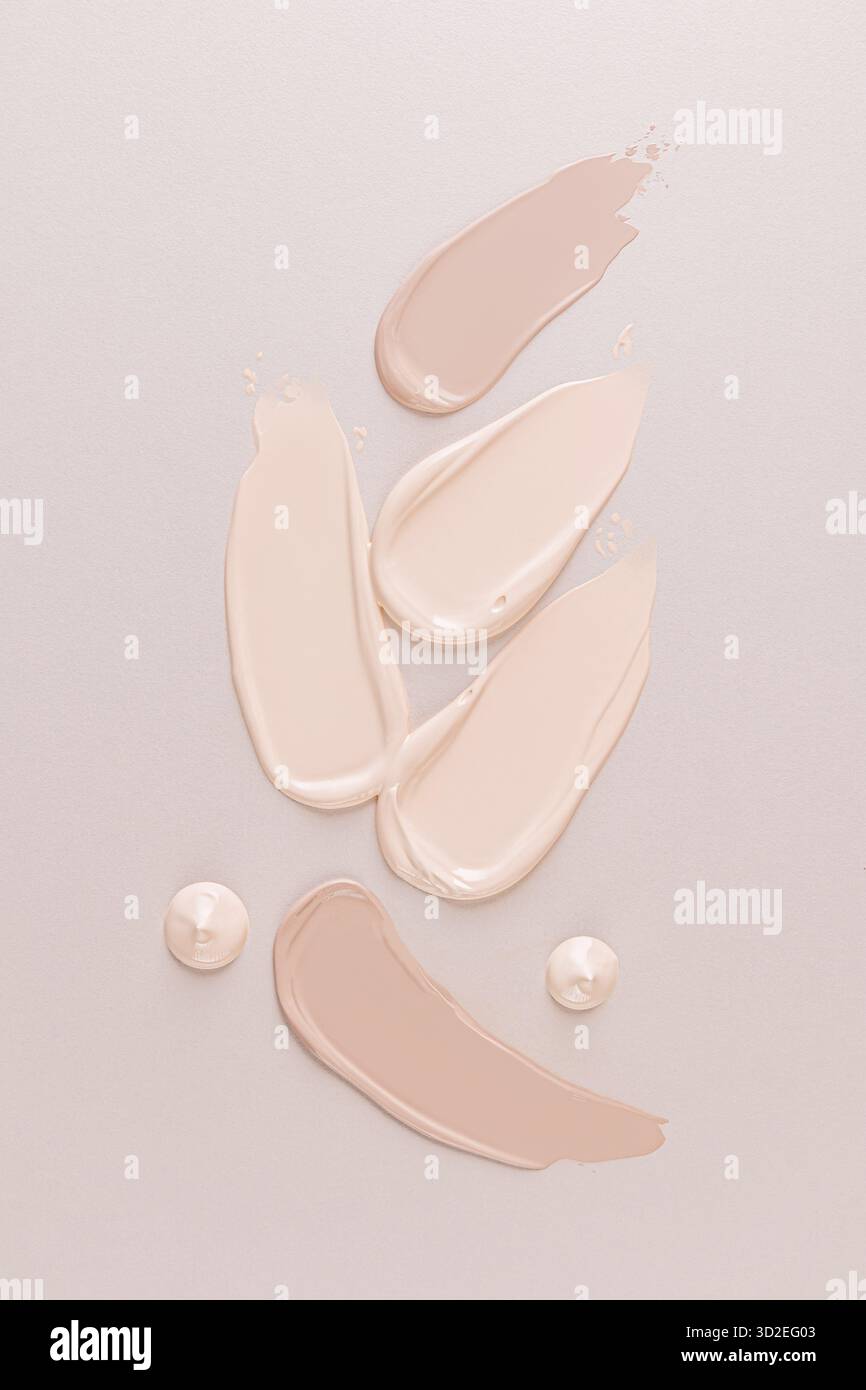 Diversi campioni di polvere liquida per fondazioni su sfondo beige con gocce di fondamento. Vista verticale superiore. Presentazione del prodotto. layout Foto Stock