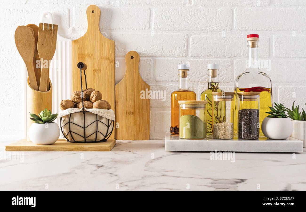 Splendido sfondo della cucina con vari oggetti moderni sullo sfondo di una parete di mattoni bianchi e un vano portaoggetti per vari tipi di olio Foto Stock