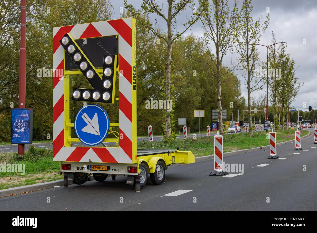 Veicolo con freccia su una strada olandese con spie che dirigono i veicoli verso sinistra durante i lavori stradali, in condizioni meteorologiche torbide. Utrecht, Paesi Bassi Foto Stock