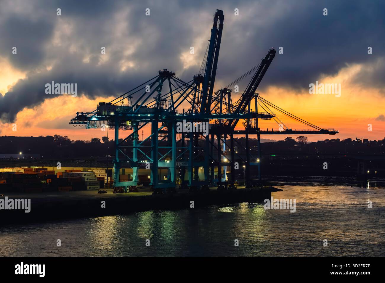 Un tramonto su uno stabilimento industriale. proietta un bagliore dorato sulle strutture metalliche. Foto Stock
