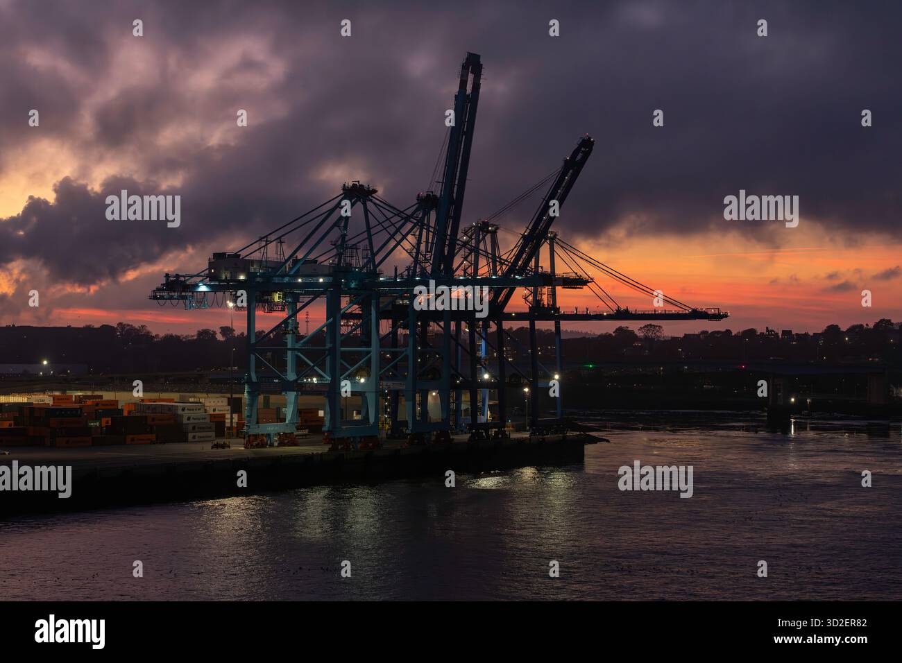 Un tramonto su uno stabilimento industriale. proietta un bagliore dorato sulle strutture metalliche. Foto Stock