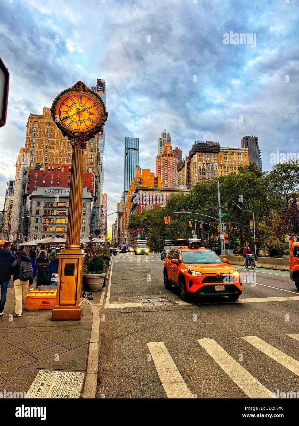 Luce serale dorata sulla Fifth Avenue vicino al Flatiron Building, New York City, con orologio da strada vintage e taxi gialli. - Immagine stock catturata con smartphone