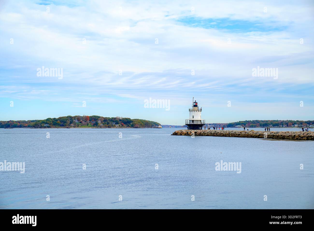 Una tranquilla vista costiera con il faro di Spring Point Ledge a Portland, Maine, che si erge alla fine di una scogliera rocciosa sotto morbide nuvole Foto Stock