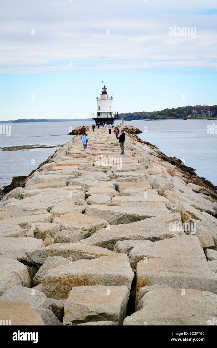 I visitatori esplorano la strada rialzata rocciosa fino a Bug Light, il faro di Portland Breakwater, mentre le dolci nuvole attraversano il cielo sopra casco Bay. Foto Stock