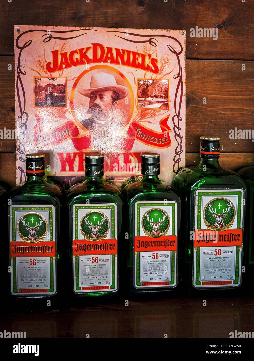 Molte bottiglie Jägermeister si trovano su Un bancone sotto Un cartello pubblicitario di Jack Daniel's. Atmosfera da night bar Foto Stock