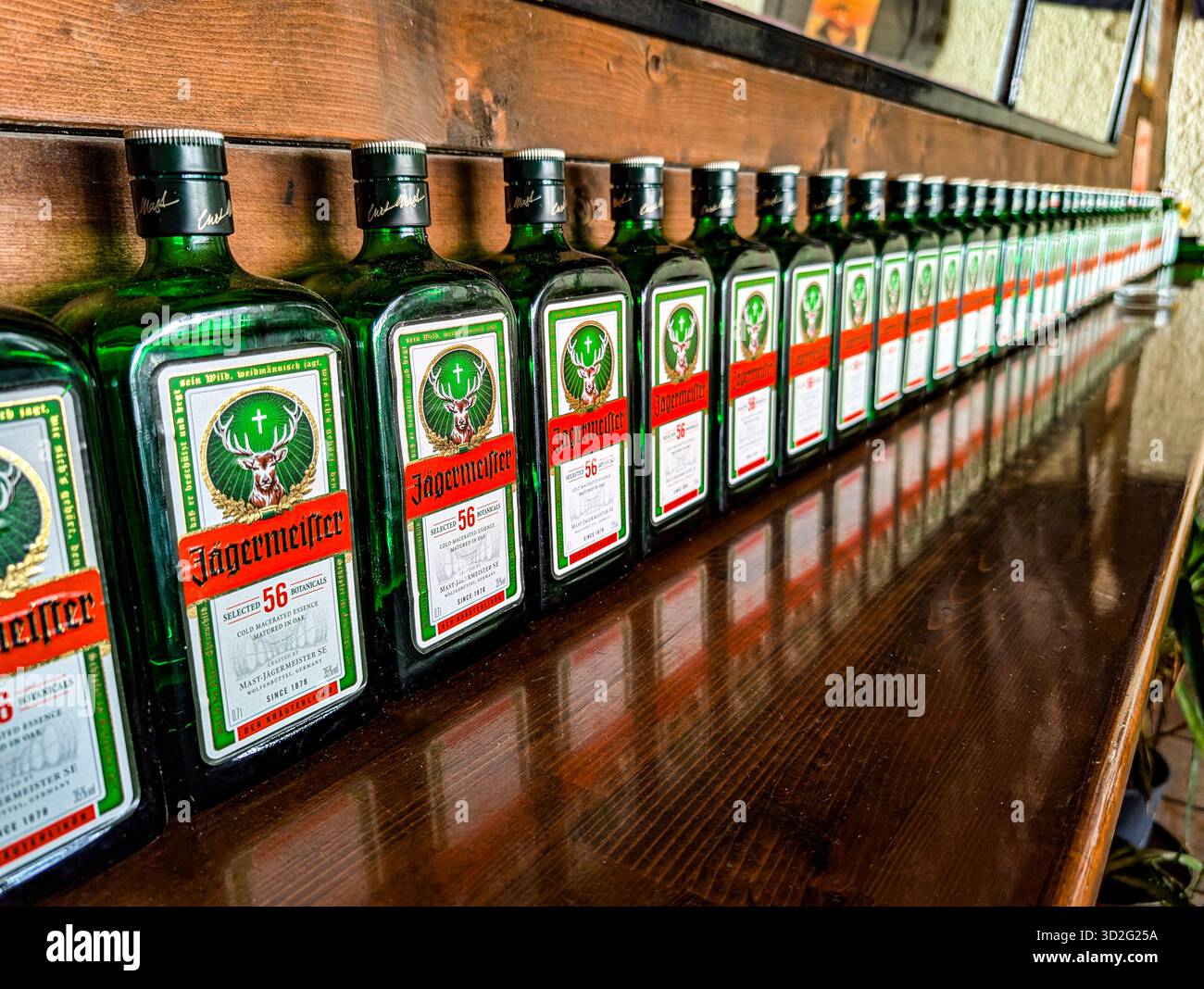 Molti flaconi Jägermeister allineati su Un bancone in legno. Atmosfera da night bar Foto Stock