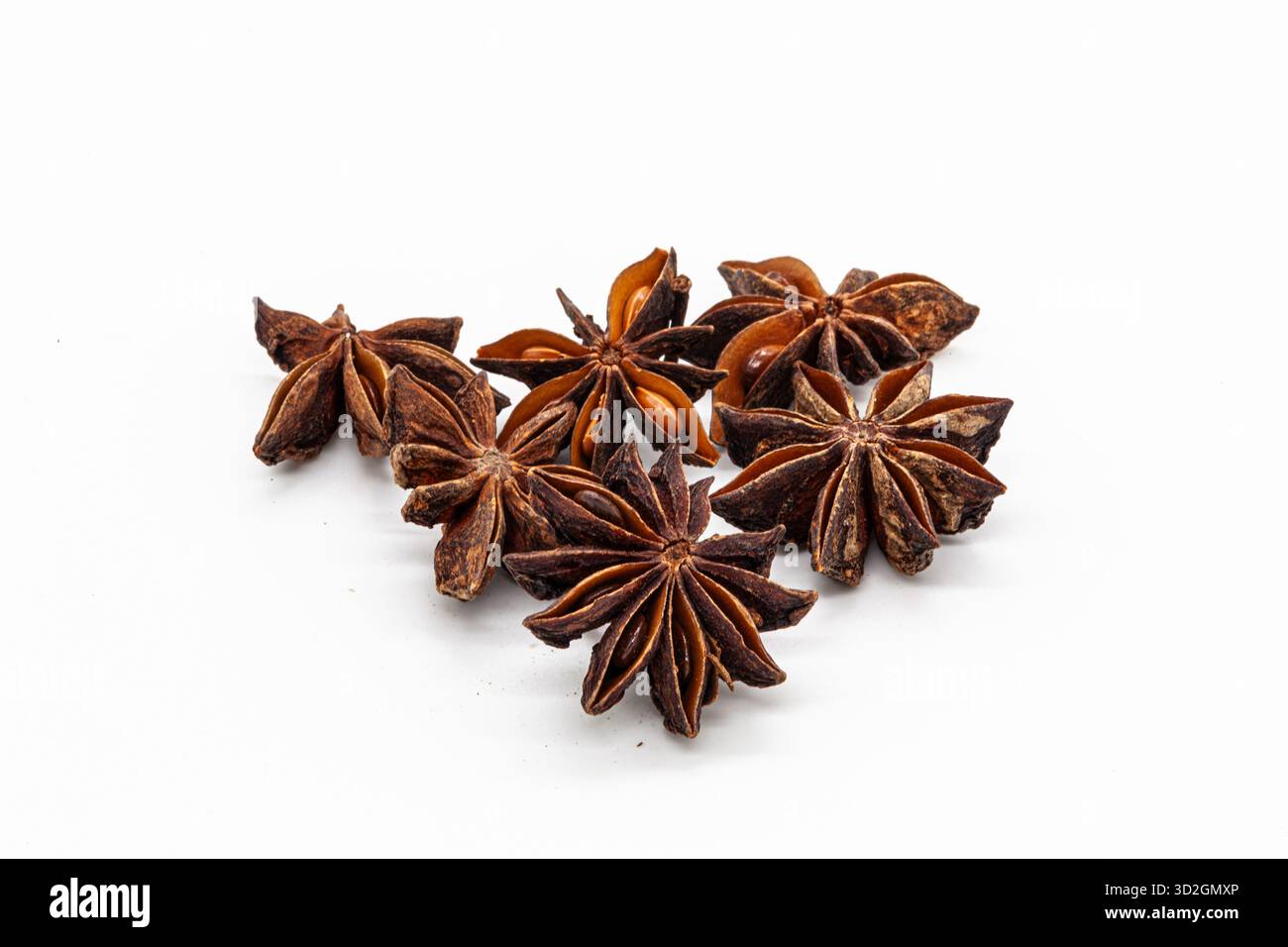Primo piano di una manciata di stelle di anice marroni essiccate. Isolata su uno sfondo bianco pulito, questa spezia è perfetta per progetti culinari e menu. Foto Stock