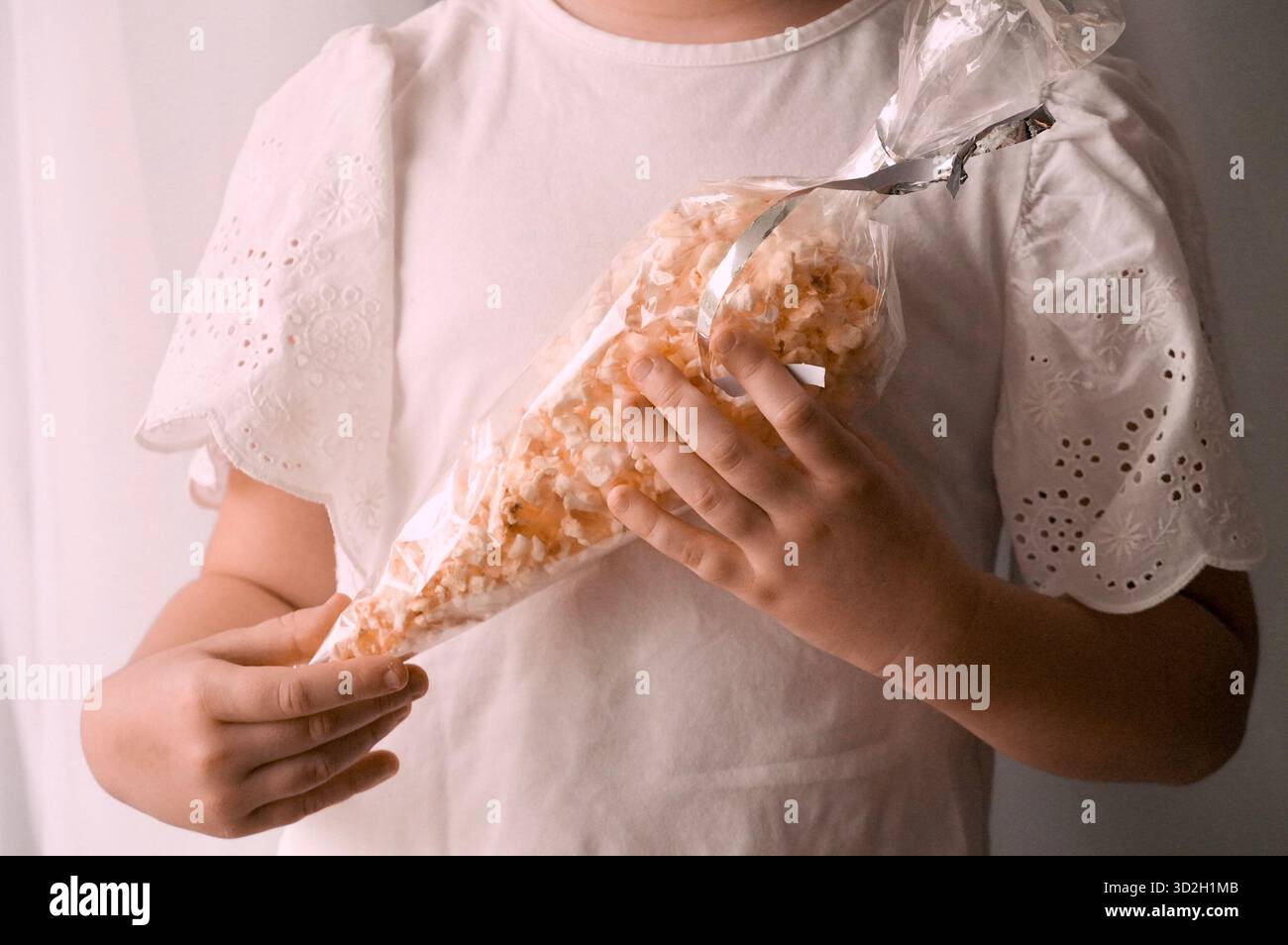Un bambino con una maglietta bianca sta mangiando un biscotto. Foto Stock