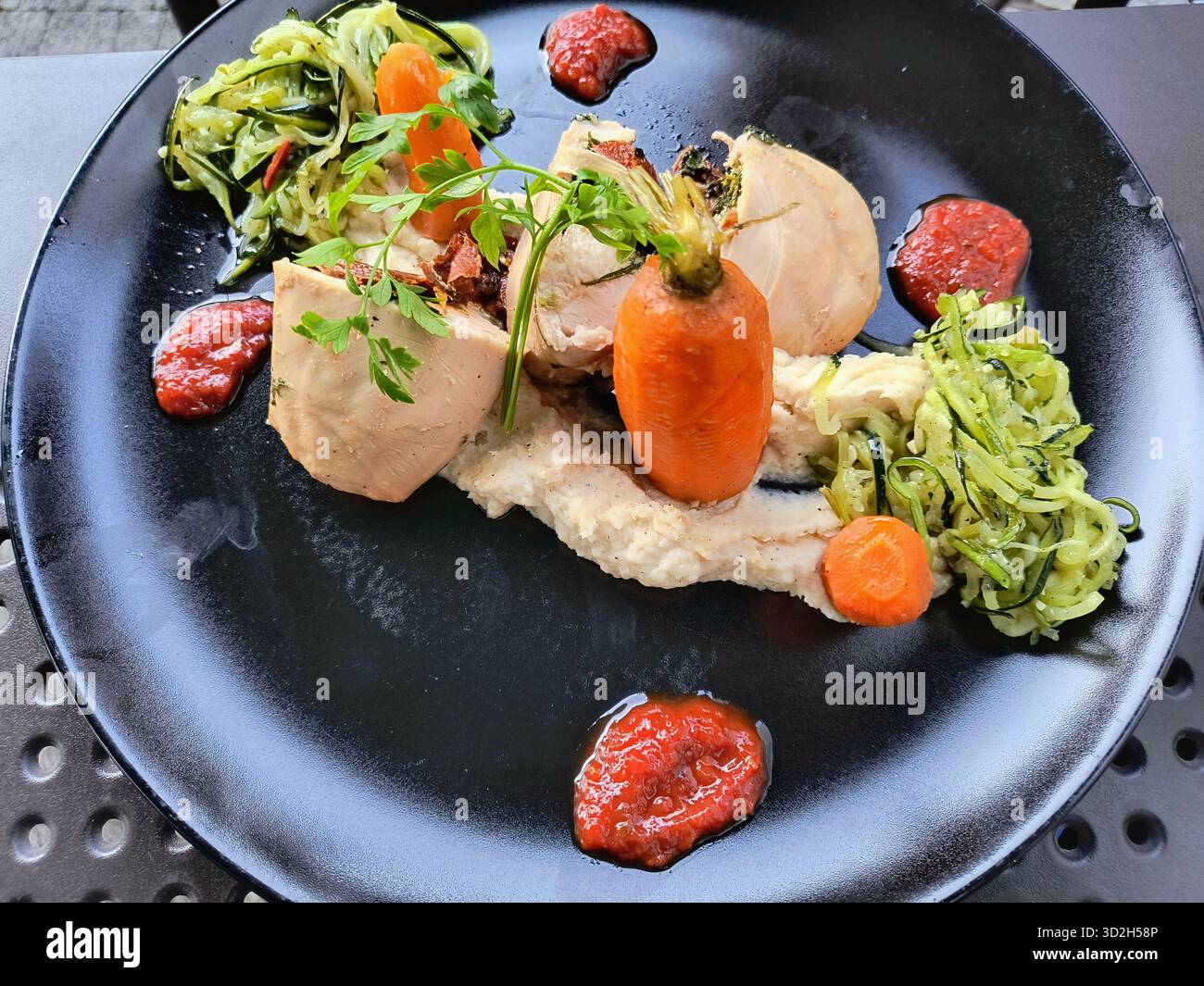 Vista dall'alto di un piatto gourmet accuratamente placcato con fette di pollo di colore chiaro (pollo o tacchino) roulade, possibilmente sous vide cotto, pre Foto Stock