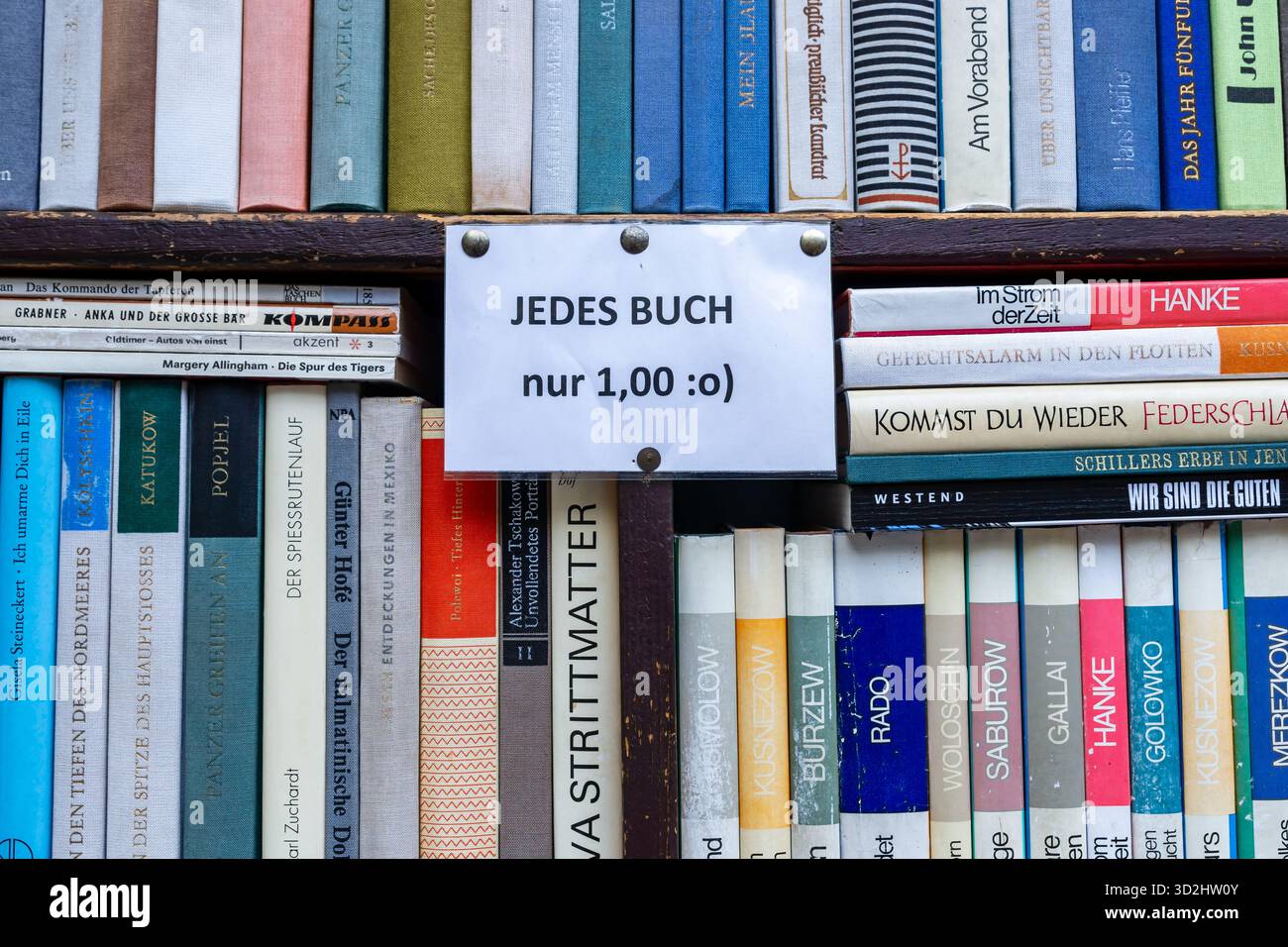 Scaffale di libri di seconda mano in una libreria antiquaria tedesca, che mostra file di libri in lingua tedesca e un'offerta scritta a mano. Foto Stock