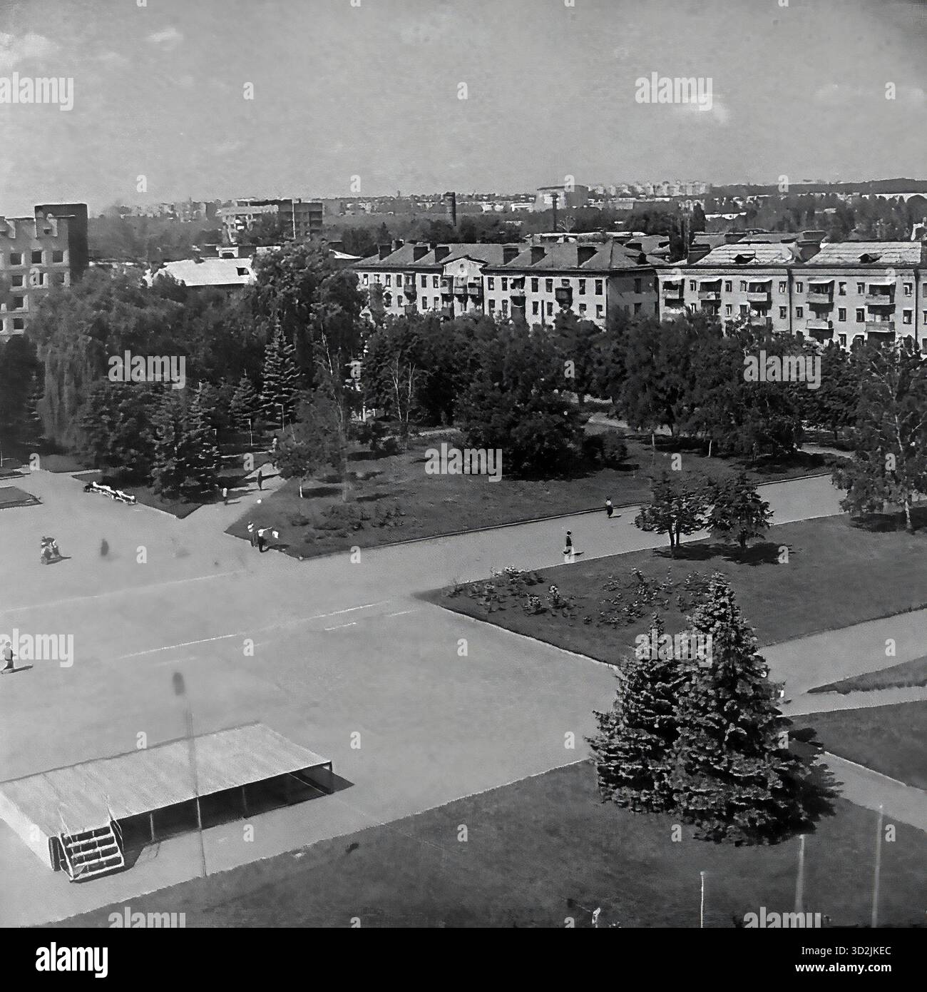Archivio foto in bianco e nero da Sloviansk, Ucraina, luglio 1997. Questa vista ad alto angolo mostra la piazza centrale della città, Piazza della Rivoluzione d'ottobre (ora Piazza Soborna). La foto cattura la grande piazza aperta, un parco (skver) con vicoli, abeti e aiuole. Un piccolo palcoscenico è in primo piano. Sullo sfondo, la piazza è incorniciata da edifici residenziali "Stalinka" (era Stalin). Questa immagine cattura una tranquilla giornata estiva in una città post-sovietica. Foto Stock