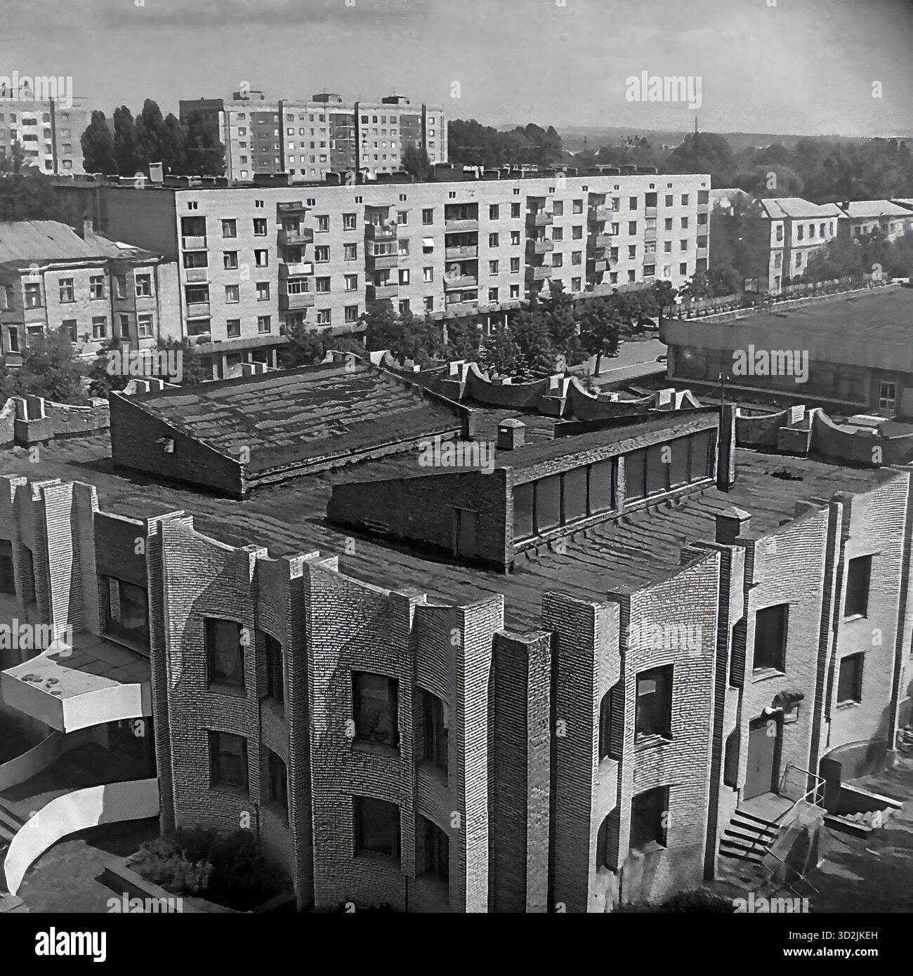 Archivio foto in bianco e nero da Sloviansk, Ucraina, luglio 1997. Questa vista ad alto angolo mostra la biblioteca centrale in Piazza della Rivoluzione d'ottobre (ora Piazza Soborna). L'edificio presenta un'architettura modernista unica in mattoni. Due donne sono sui gradini. Sullo sfondo ci sono vecchi edifici dell'epoca Stalin e nuovi blocchi di appartamenti sovietici, circondati da alberi estivi. Questo cattura il paesaggio urbano di una città post-sovietica. Foto Stock