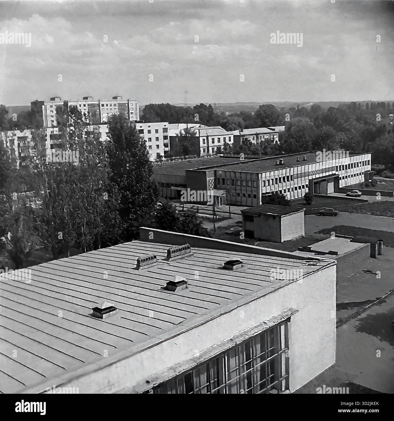 Archivio foto in bianco e nero da Sloviansk, Ucraina, luglio 1997. Questa vista ad alto angolo, presa dalla piazza centrale, si affaccia su via Lenin (ora via Universitetskaya). Al centro si trova il lungo edificio modernista del grande magazzino "Univermag". Lo sfondo presenta un mix di edifici residenziali a più piani e architettura più antica, circondati da alberi estivi. Questo cattura il centro commerciale e residenziale della città post-sovietica. Foto Stock