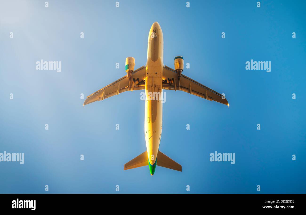 L'immagine mostra un velivolo catturato dal basso, con il sottoscocca e il carrello di atterraggio chiaramente visibili contro un cielo azzurro. La luce del sole lo è Foto Stock