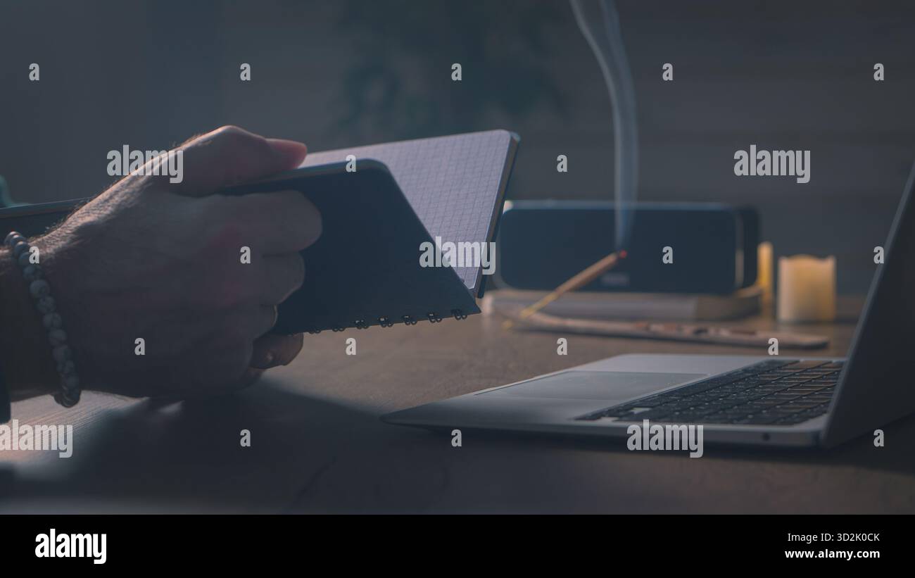 Solitudine creativa. Le mani scrivono lentamente in un notebook, lo schermo balla sulle pagine, il calore soffice della stanza e la messa a fuoco silenziosa Foto Stock