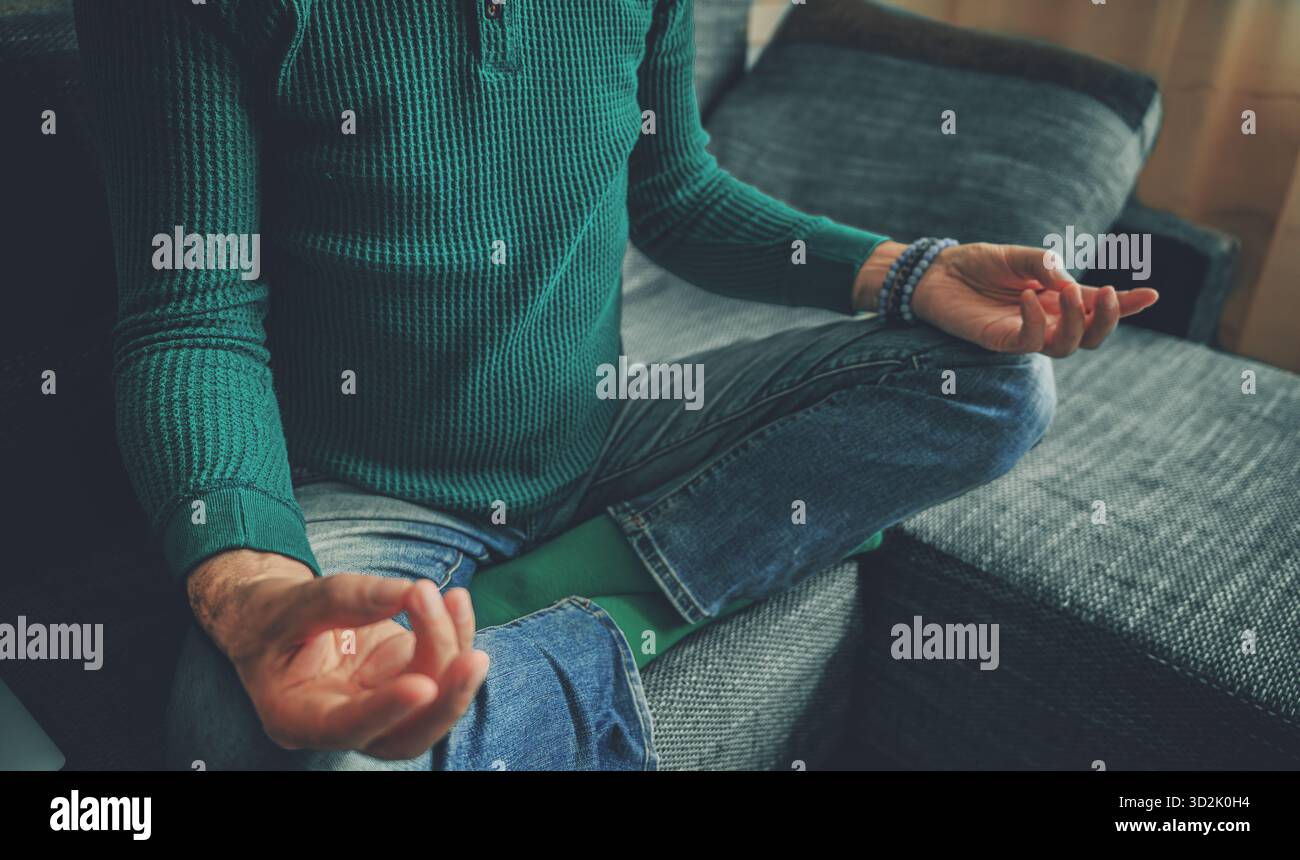 Il giovane che meditava a Padmasana poggia a casa, circondato da una luce naturale calma, simboleggia la consapevolezza, la pace e l'equilibrio spirituale Foto Stock