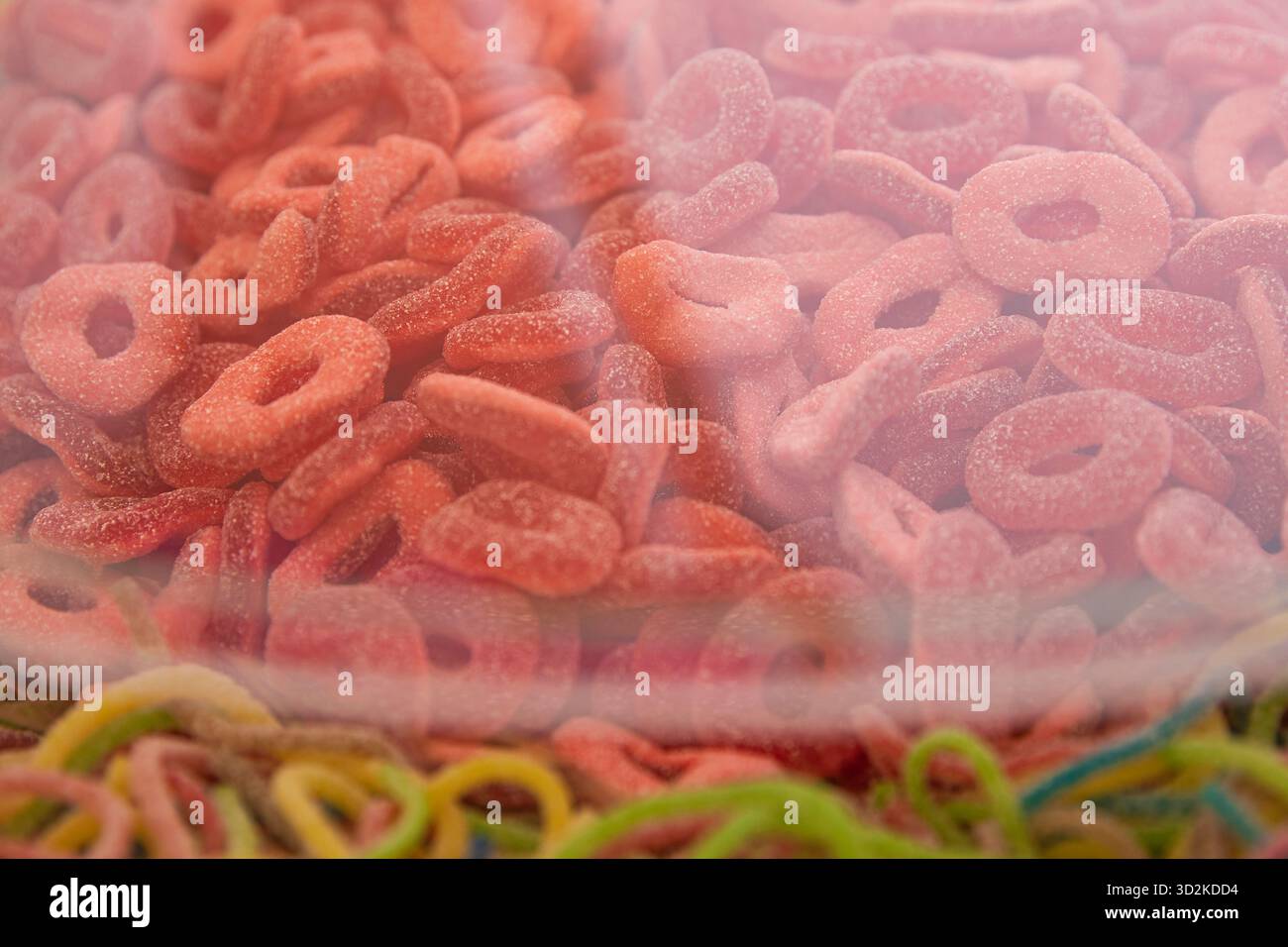 Caramelle ad anello in gelatina rossa con rivestimento di zucchero in contenitore di plastica trasparente Foto Stock