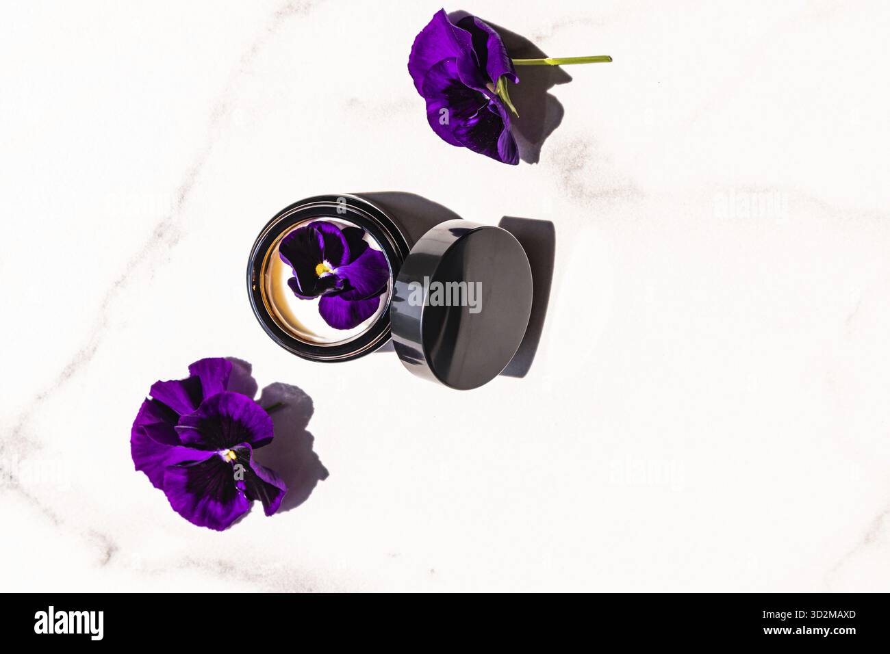 Vaso aperto in vetro scuro con crema anti-invecchiamento per la cura della pelle del viso. nutrire la pelle. cosmetici naturali. Vista dall'alto. sfondo di marmo Foto Stock