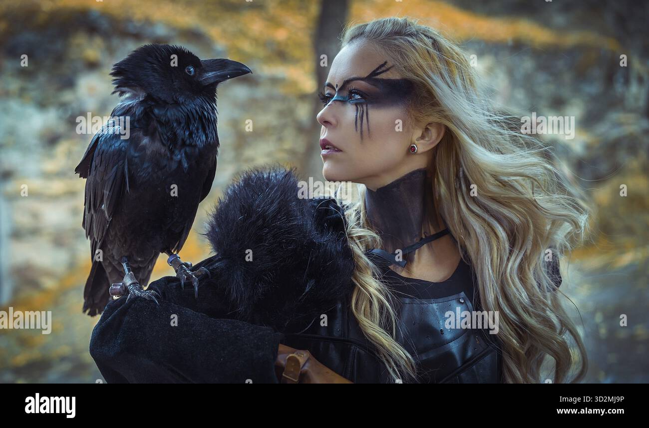 Bella corvo nero, donna bionda vichinga con scudo e spada, trecce nei capelli Foto Stock