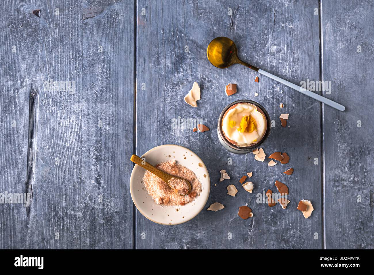 Uovo bruno sodo in cui la parte superiore viene tagliata in una tazza grigia su sfondo grigio, vista dall'alto, spazio di copia Foto Stock