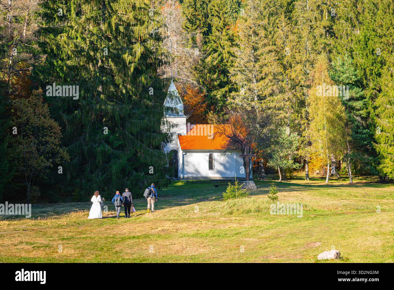 Affascinante scena di nozze in una cappella nella foresta con sposi e ospiti Foto Stock