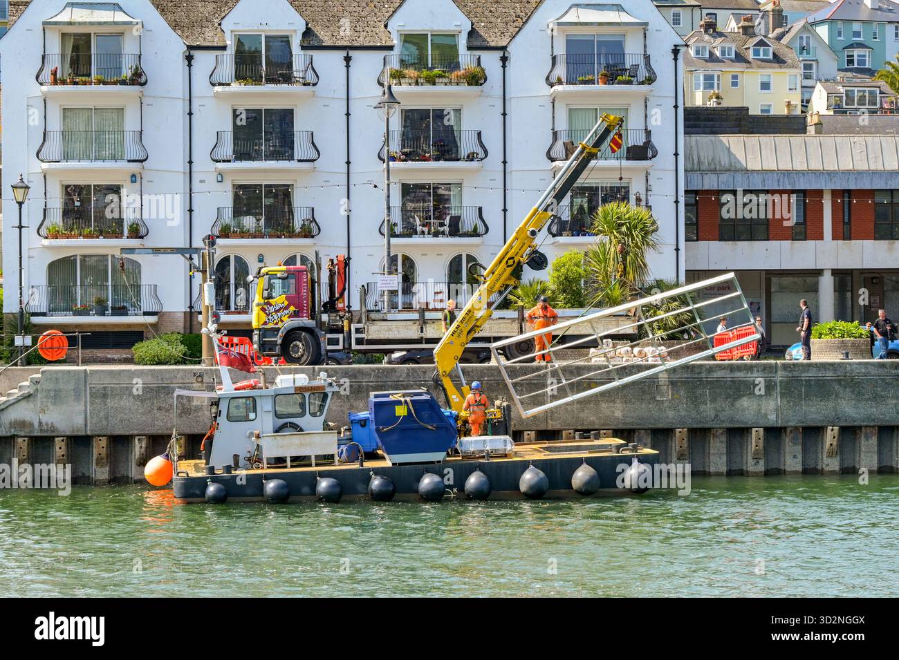 Dartmouth, Devon, Inghilterra, Regno Unito - 24 aprile 2025: Piccola imbarcazione industriale con gru idraulica sul ponte che carica una struttura sul ponte del Rive Foto Stock