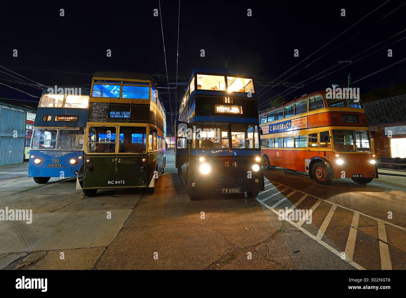 Una fila di filobus durante un evento al crepuscolo al Sandtoft Trolleybus Museum nel North Lincolnshire, Regno Unito Foto Stock