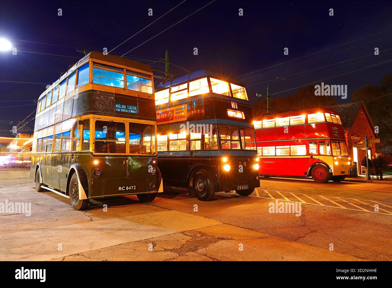 Una fila di filobus durante un evento al crepuscolo al Sandtoft Trolleybus Museum nel North Lincolnshire, Regno Unito Foto Stock