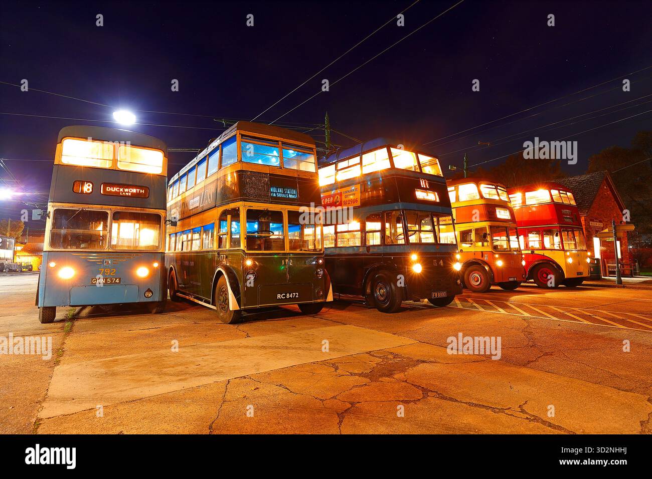 Una fila di filobus durante un evento al crepuscolo al Sandtoft Trolleybus Museum nel North Lincolnshire, Regno Unito Foto Stock